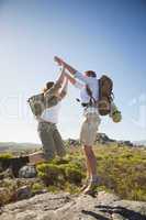 Hiking couple jumping and cheering on rocky terrain