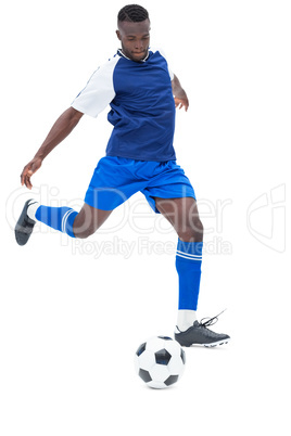 Football player in blue kicking ball