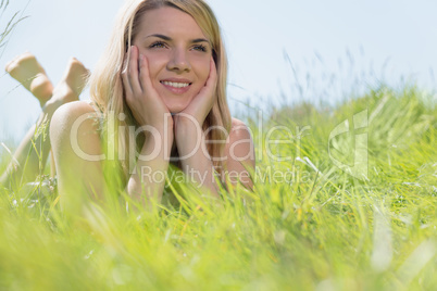 Pretty blonde in sundress lying on grass smiling