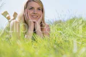 Pretty blonde in sundress lying on grass smiling