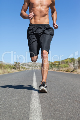 Shirtless man jogging on open road