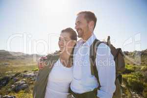 Hiking couple embracing and smiling on country terrain