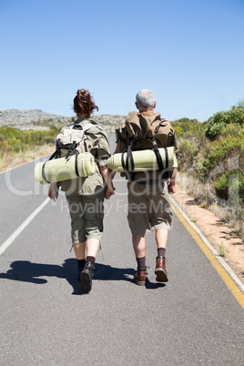 Hitch hiking couple holding hands on the road