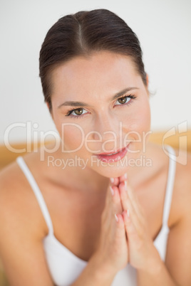 Smiling brunette meditating with hands together