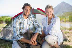 Attractive hiking couple smiling at camera outside their tent