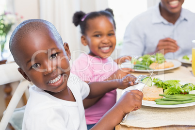 Family enjoying a healthy meal together with son smiling at came