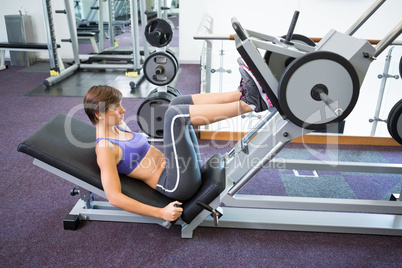 Fit brunette using weights machine for legs