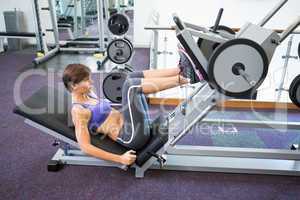 Fit brunette using weights machine for legs