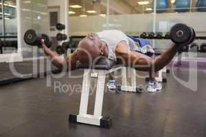 Muscular man exercising with dumbbells