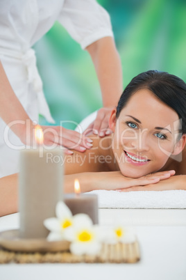 Beautiful brunette enjoying a back massage smiling at camera