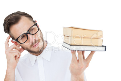 Geeky young man looking at pile of books