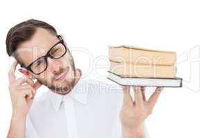 Geeky young man looking at pile of books
