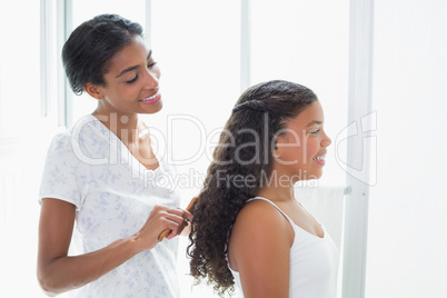 Pretty mother brushing her daughters hair