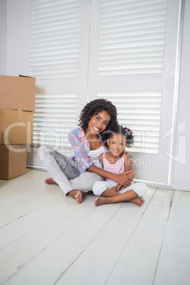 Mother and daughter sitting on the floor smiling at camera
