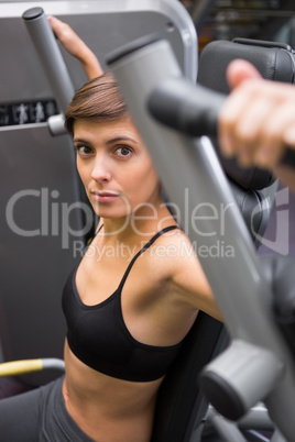 Serious brunette using weights machine for arms Serious brunette using weights machine for arms