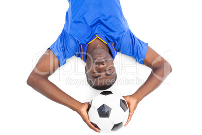 Football player lying on the ground holding ball with eyes close