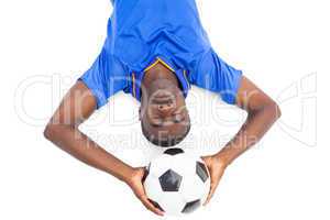 Football player lying on the ground holding ball with eyes close