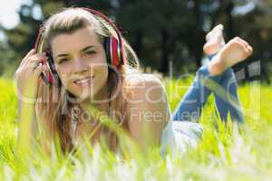 Pretty blonde lying on grass listening to music