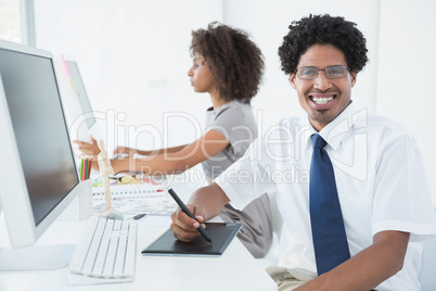 Young designer smiling at camera at his desk