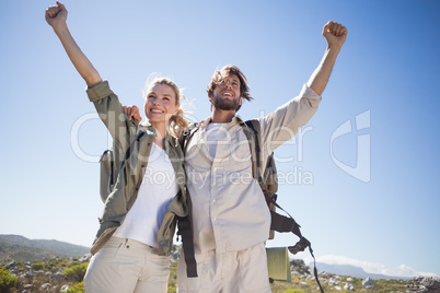 Hiking couple standing on mountain terrain cheering