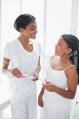 Pretty mother brushing her teeth with her daughter