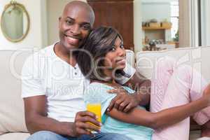 Happy couple relaxing on the couch with juice