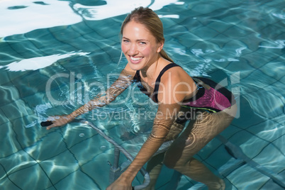 Fit happy blonde using underwater exercise bike