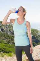 Fit blonde taking a break at summit drinking water