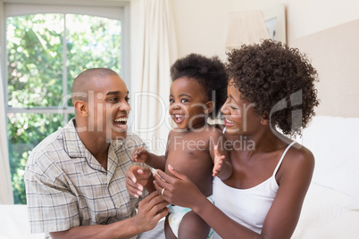 Happy couple on bed with baby daughter