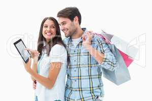 Attractive young couple with shopping bags and tablet pc
