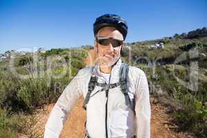 Fit cyclist smiling at the camera on country terrain