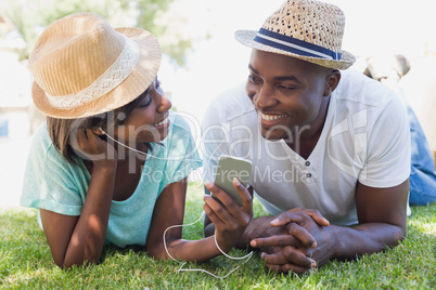 Happy couple lying in garden together listening to music