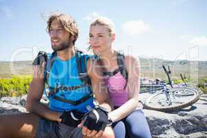 Fit cyclist couple taking a break on rocky peak