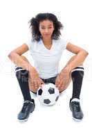 Pretty football player in white sitting on floor with ball