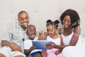 Happy family using tablet together on bed