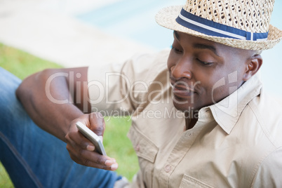 Happy man relaxing in his garden texting on phone