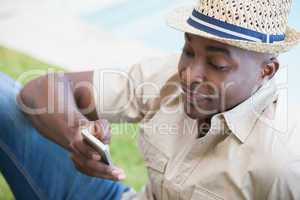 Happy man relaxing in his garden texting on phone