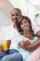 Happy couple sitting on couch having juice