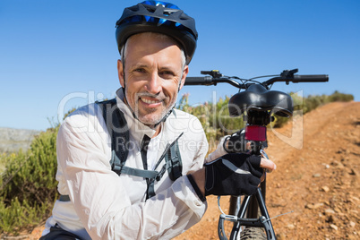 Fit cyclist carrying his bike on country terrain