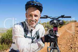 Fit cyclist carrying his bike on country terrain