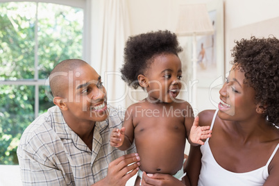 Happy couple on bed with baby daughter