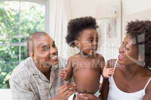 Happy couple on bed with baby daughter