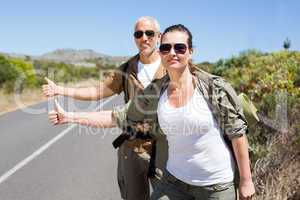 Hitch hiking couple standing on the side of the road with thumb