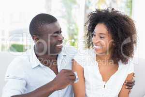 Attractive couple sitting on couch together holding credit card
