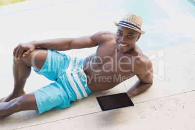 Handsome shirtless man using tablet pc poolside