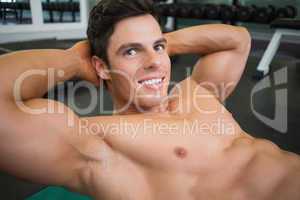 Smiling muscular man doing abdominal crunches