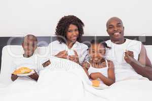 Happy family having breakfast in bed