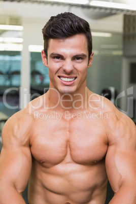 Smiling shirtless muscular man in gym