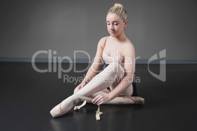 Pretty ballerina tying the ribbon on her ballet slippers