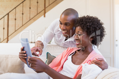 Cute couple relaxing on couch with tablet pc